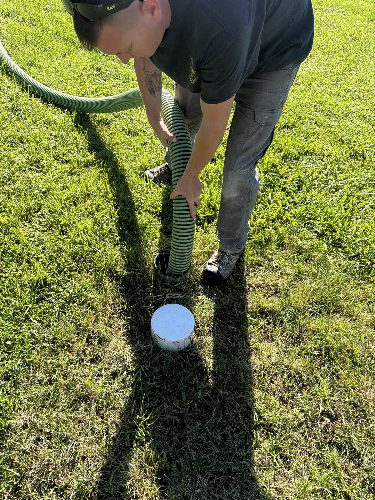 Technician coupling a vacuum hose at a septic riser