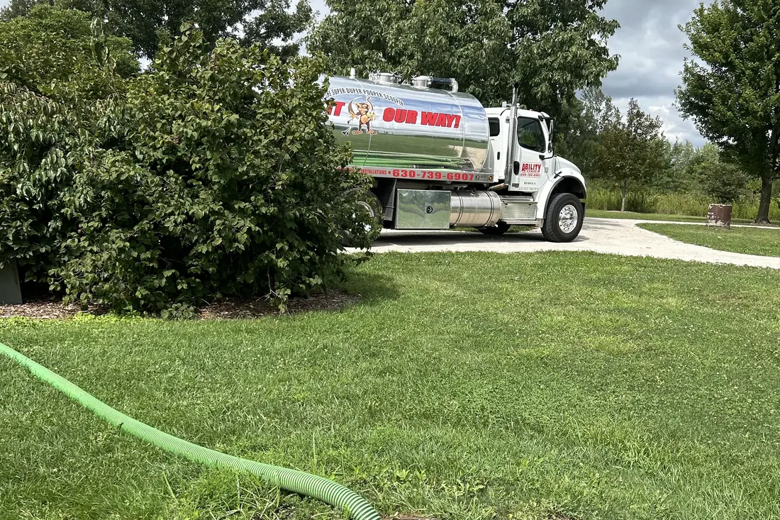 Truck and hose on a tidy summer lawn during a pump-out